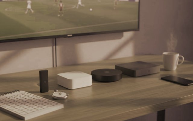 Five streaming devices, a notebook scoring grid and a stopwatch in front of a TV showing a football match