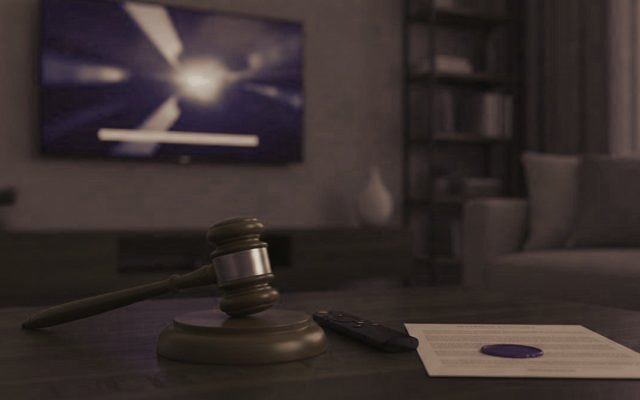 A judge gavel, a streaming remote and a sealed document on a coffee table in front of a TV